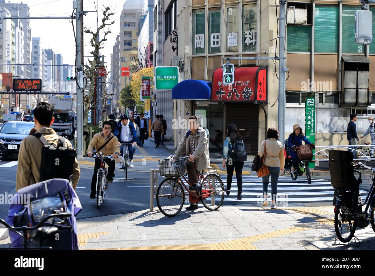 A busy street corner with pedestrians and cyclists in Ryogoku district, Sumida, Tokyo,Japan Stock Photo