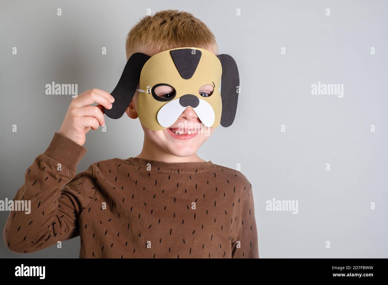 portrait of a boy smiling without a tooth in a dog mask. isolated on gray background Stock Photo