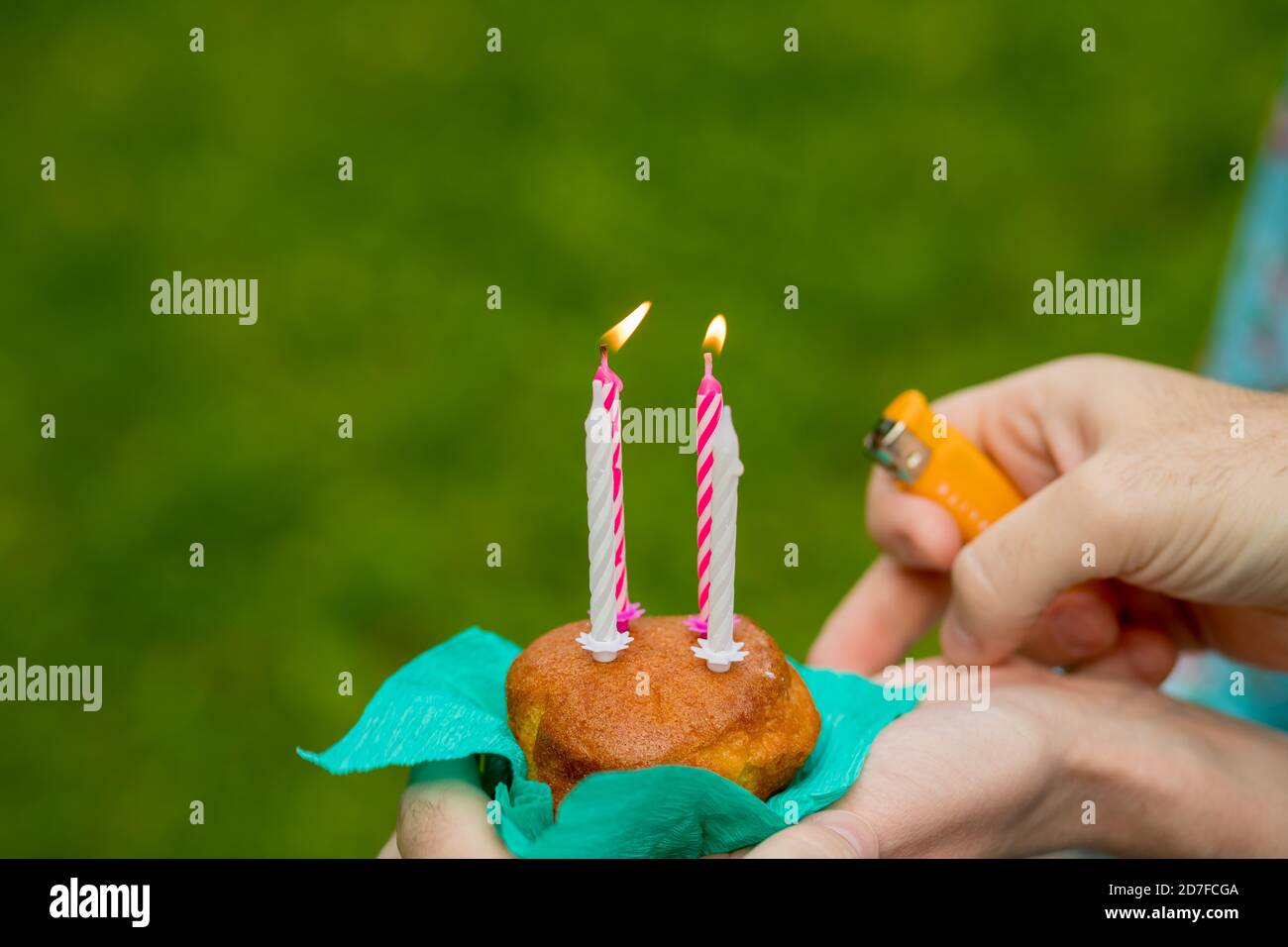 hand with a lighter to light the candle blueberry muffins on green