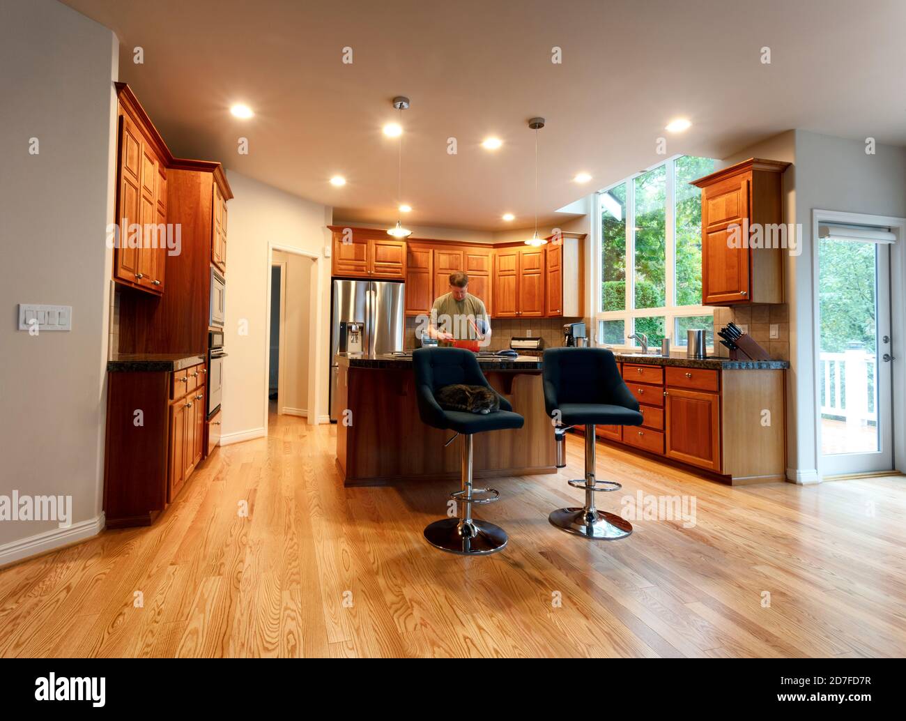 Mature man cooking in kitchen with family pet cat sleeping chair Stock Photo