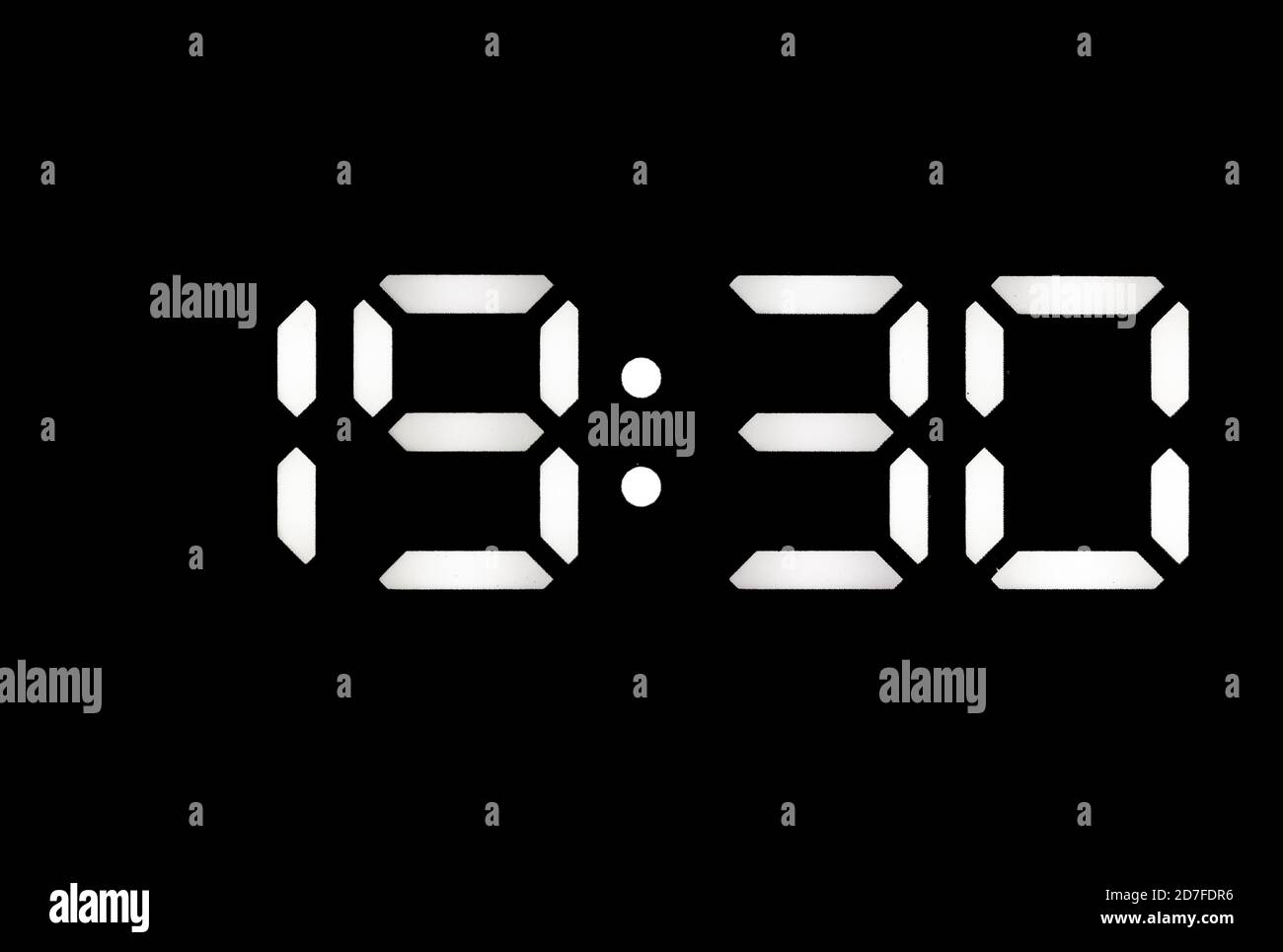 Real white led digital clock on a black background showing time 19:30 Stock Photo