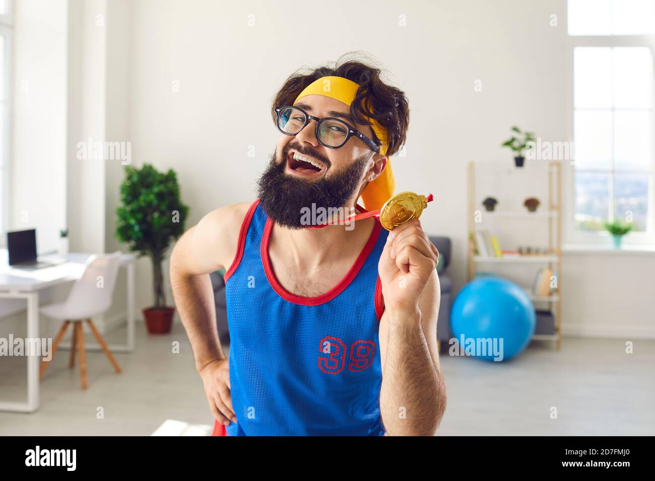 Portrait of a crazy emotional joyful athlete man holding a medal in his hand and flaunting it. Stock Photo