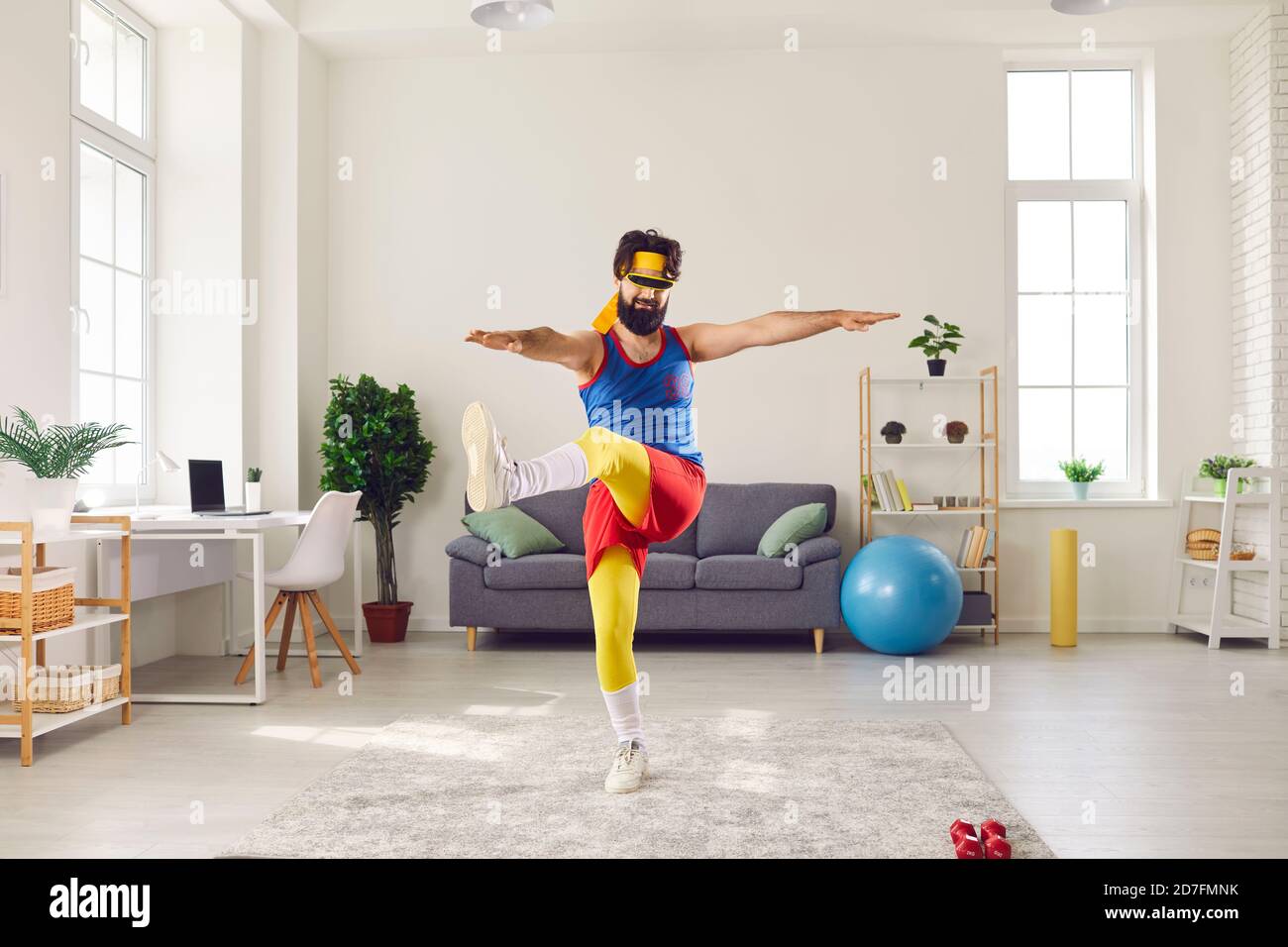 Eccentric male trainer doing exercises in front of webcam recording video for his sports blog. Stock Photo