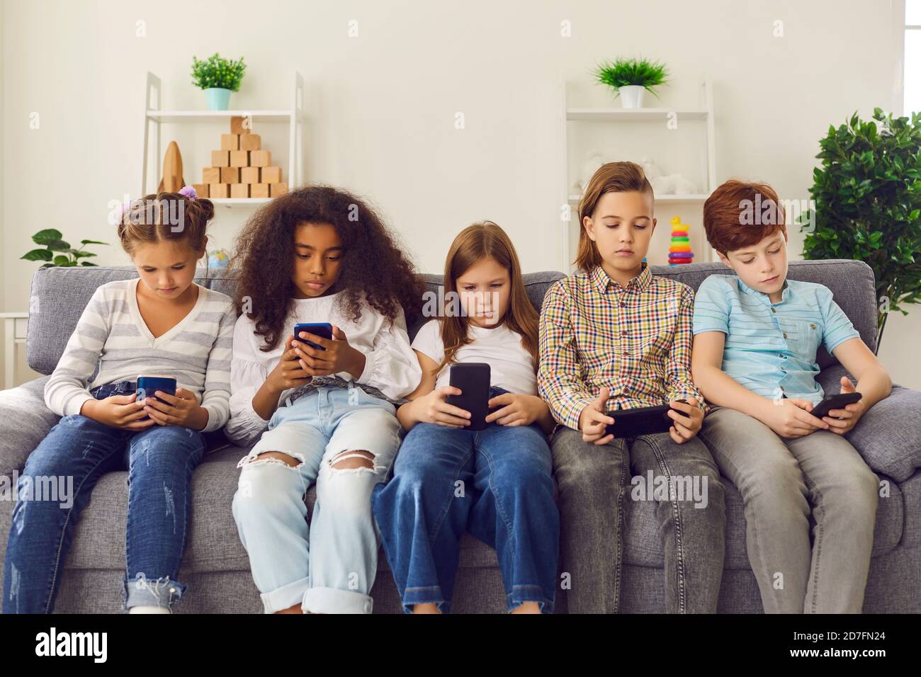 Group of unhappy children play online games or read social networks on mobile phones. Stock Photo