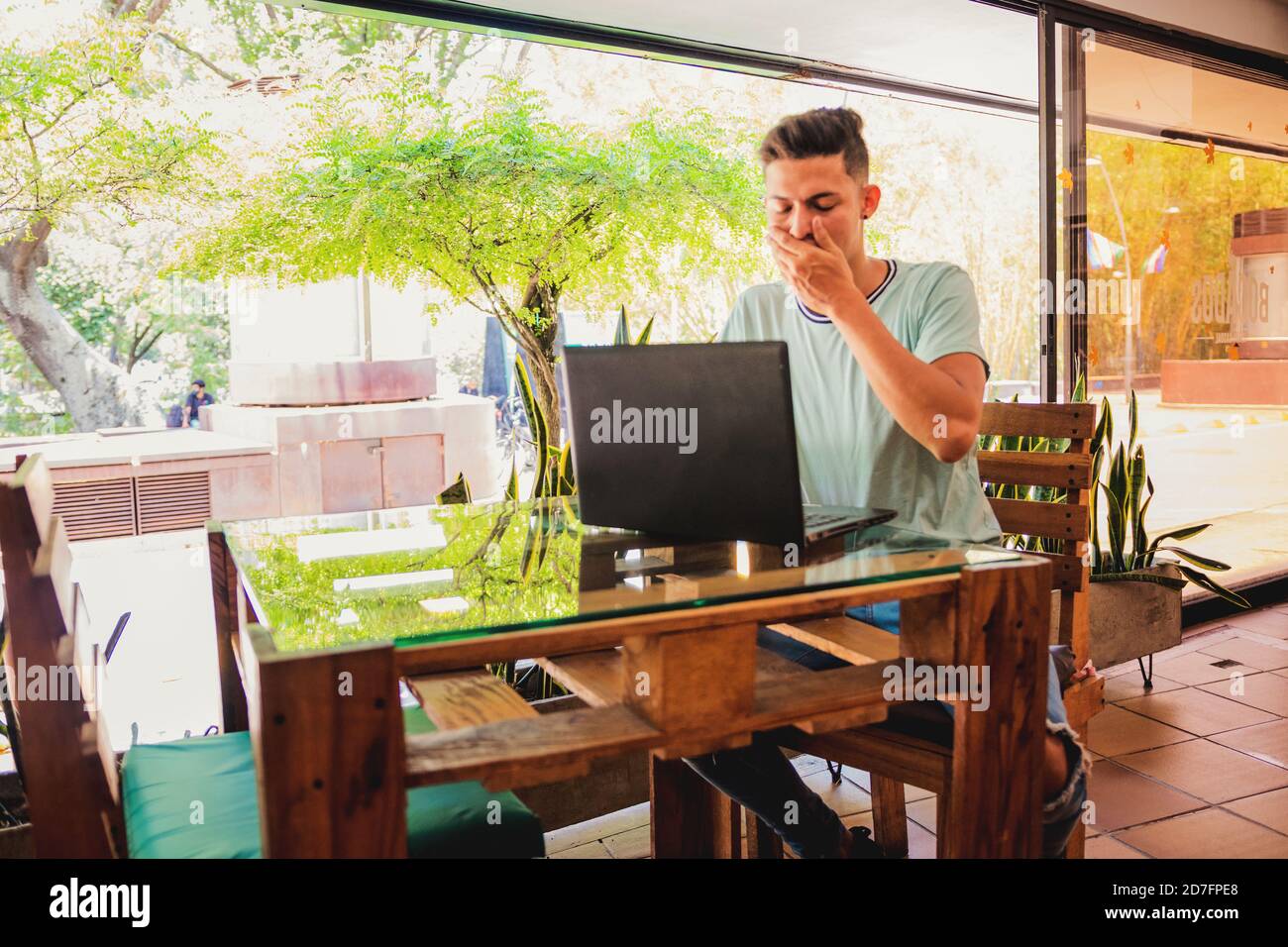 Young Hispanic man yawning while working during the quarantine Stock Photo