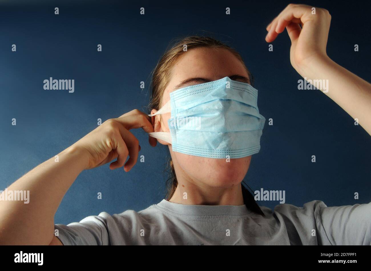 Teenage girl holding a face mask covering all her  face  during the corona virus or Covid-19 pandemic - concept image Stock Photo