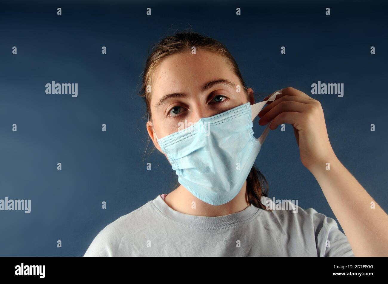 Teenage girl holding a face mask in her hands in front of her face for infection control during the coronavirus or Covid-19 pandemic Stock Photo