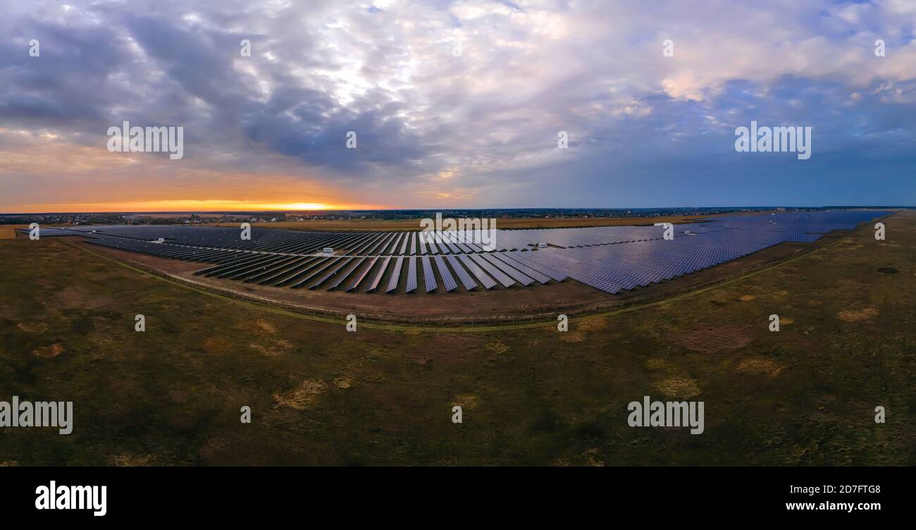 Aerial panorama view of large solar panels at a solar farm at bright summer sunset. Solar cell power plants, colorful photo Stock Photo