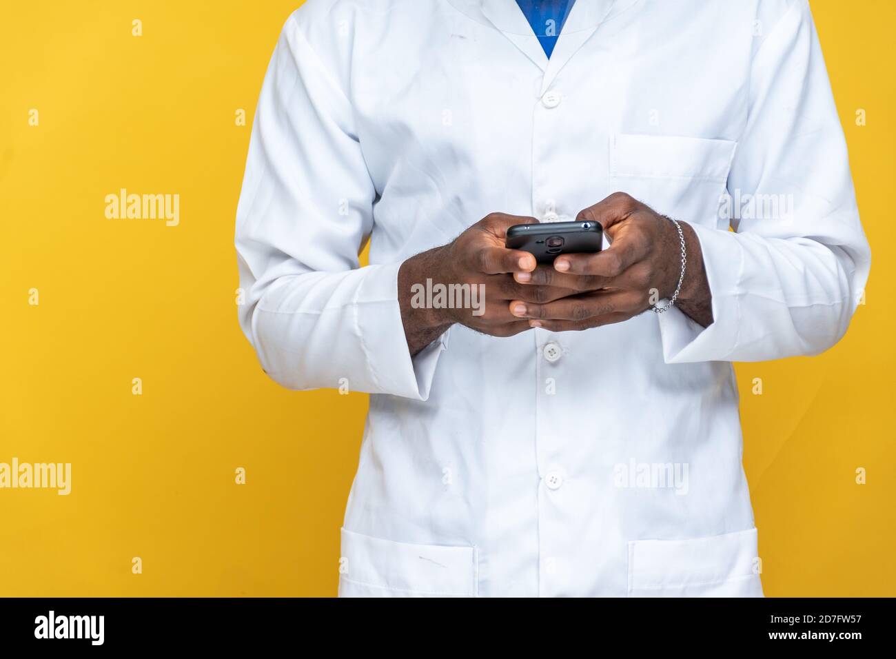 closeup of a young black man in a lab coat using his phone Stock Photo