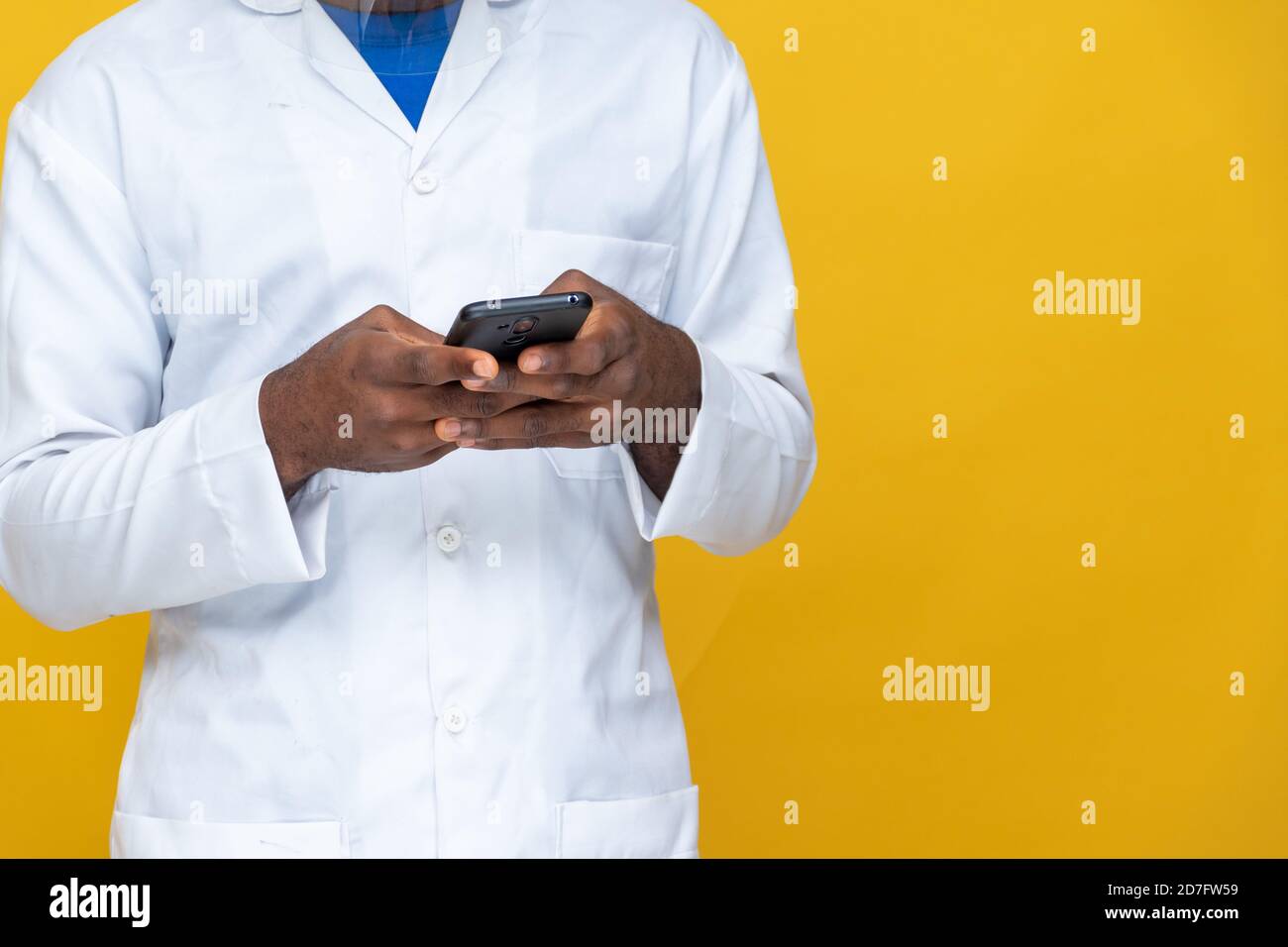 closeup of a young african man in a lab coat using his phone Stock Photo