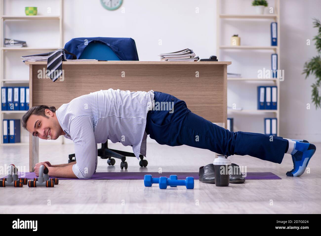 Handsome male employee doing exercises in the office Stock Photo