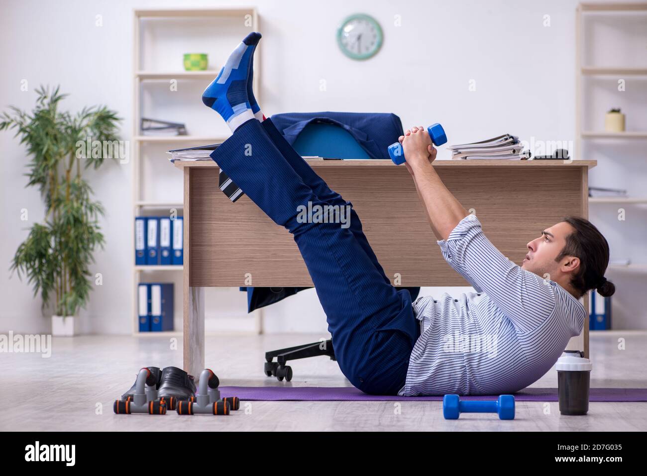 Handsome male employee doing exercises in the office Stock Photo
