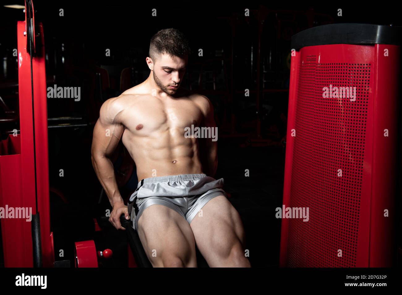 Strong Man In The Gym And Exercising Quadriceps And Glutes On Machine