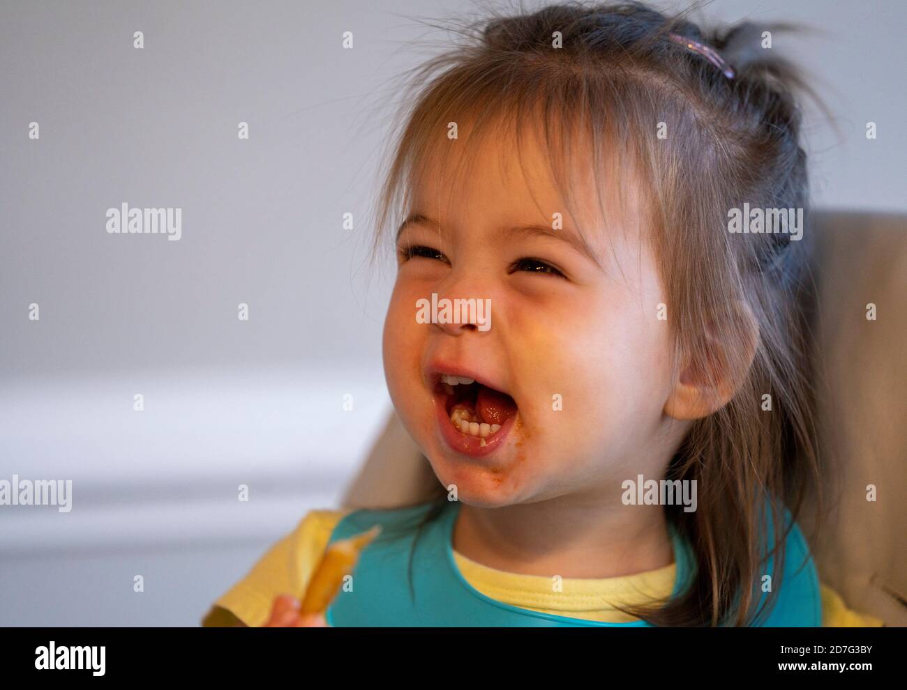 Cute two year old girl puts on her funny faces during snack time Stock
