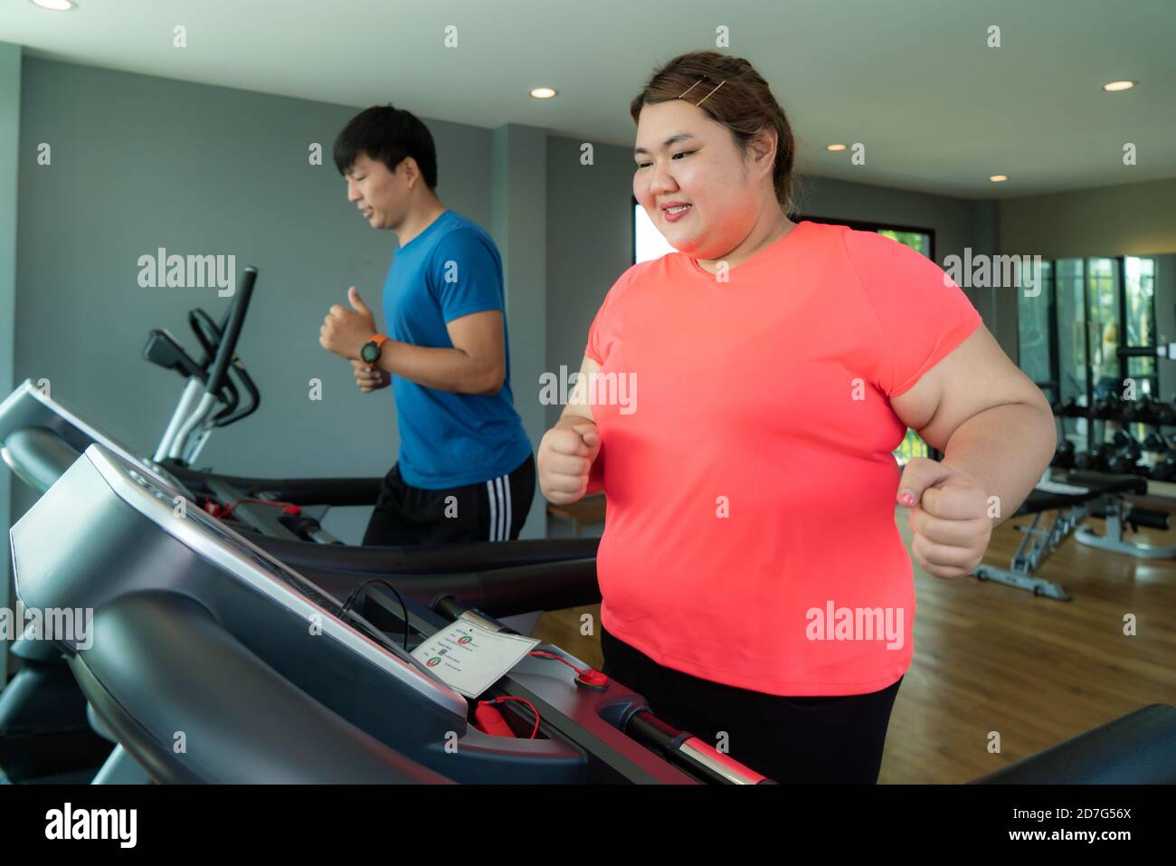 Two Asian trainer man and Overweight woman exercising training on treadmill in gym. Fat women take care of health and want to lose weight. Stock Photo