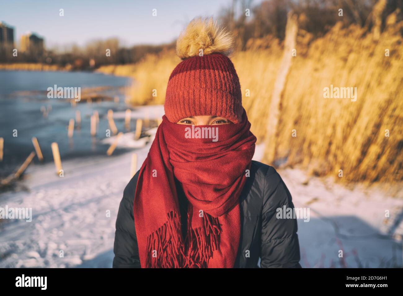 Winter cold weather protection girl with face and head completely covered with warm scarf and beanie hat. Funny portrait outdoor portraying intense Stock Photo