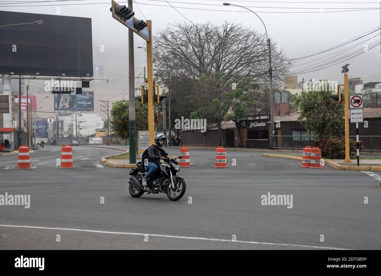 Daily street life scenes of the new normal. Young man riding a motorbike on a quiet road due to restrictions in Lima, Perú. Stock Photo