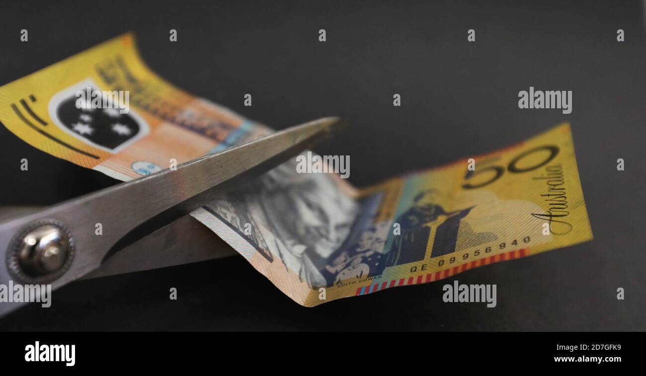Australian 50 fifty dollar note about to be cut with scissors. tax cut saving spending cuts divorce and separation settllement concept. Budget stress Stock Photo