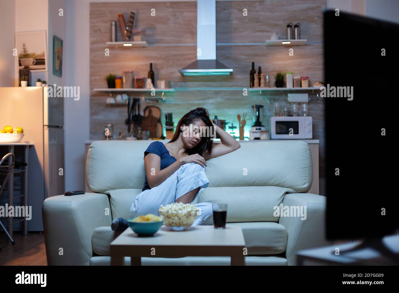 Caucasian woman falling asleep on sofa at home while watching TV. Tired