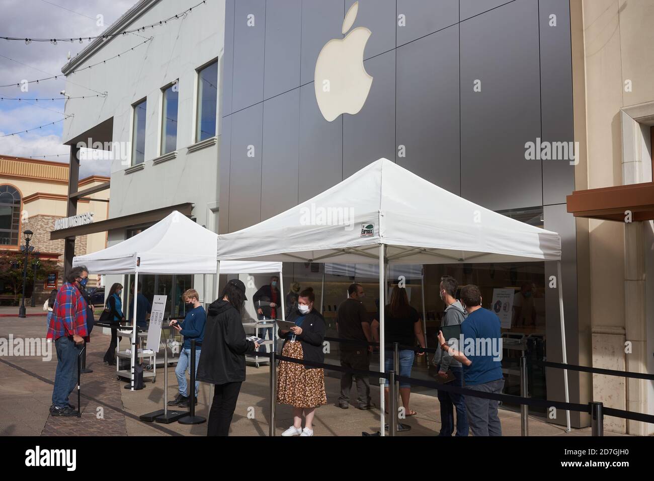 Shoppers check in before entering the Apple store in Tigard, Oregon, during a pandemic fall season. The new iPhone 12 is to be released on Friday. Stock Photo
