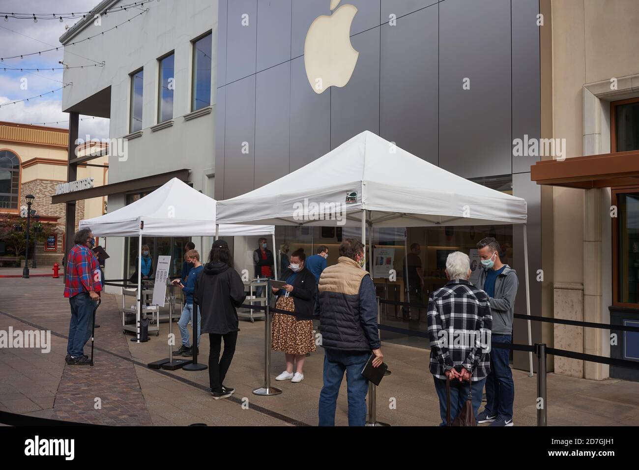 Shoppers check in before entering the Apple store in Tigard, Oregon, during a pandemic fall season. The new iPhone 12 is to be released on Friday. Stock Photo