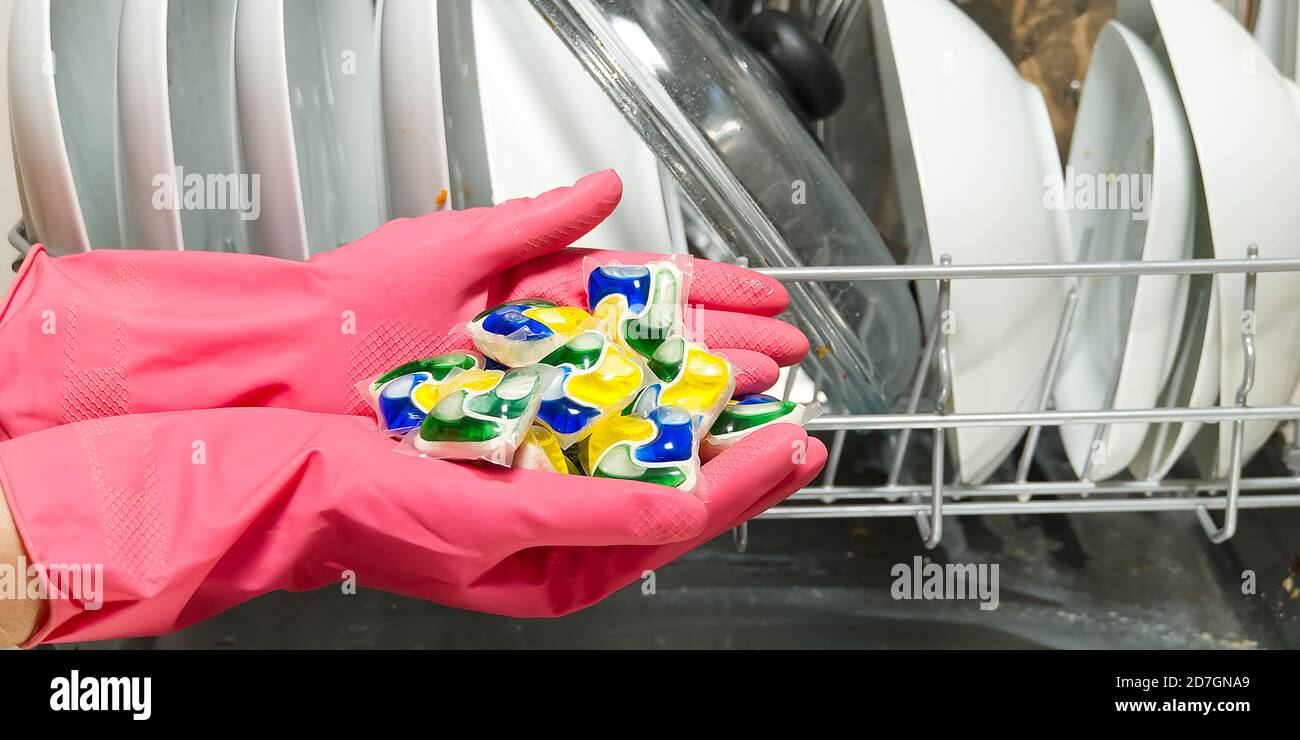 Dishwasher Detergents in hands. hands in pink golvs holds dishwasher