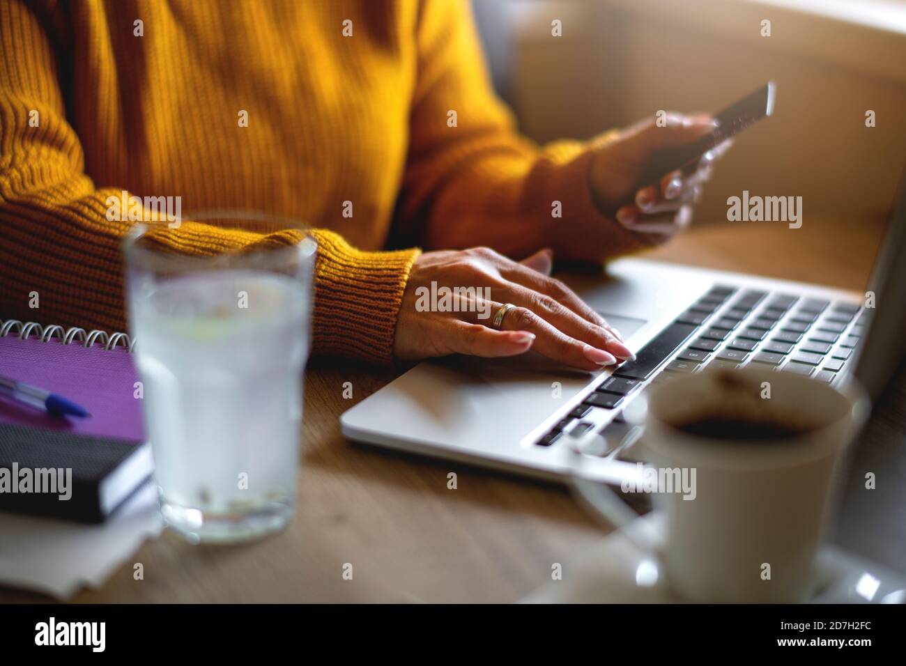 Unrecognizable person's hand holding credit card in front of lap top at home Stock Photo