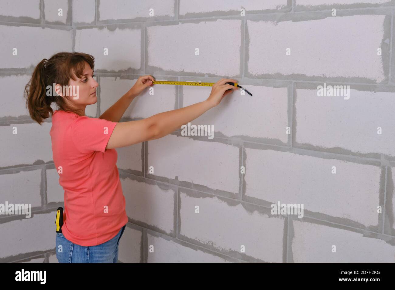 A woman measures the length of the wall in a new apartment. Distance ...