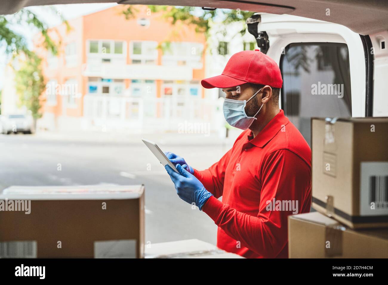 Delivery man wearing face protective mask to avoid corona virus spread - Young express courier working during coronavirus outbreak Stock Photo