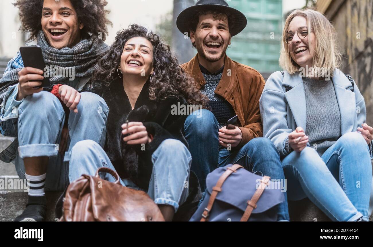 Young friends using phone and talking together outdoor - Youth social people and technology concept Stock Photo