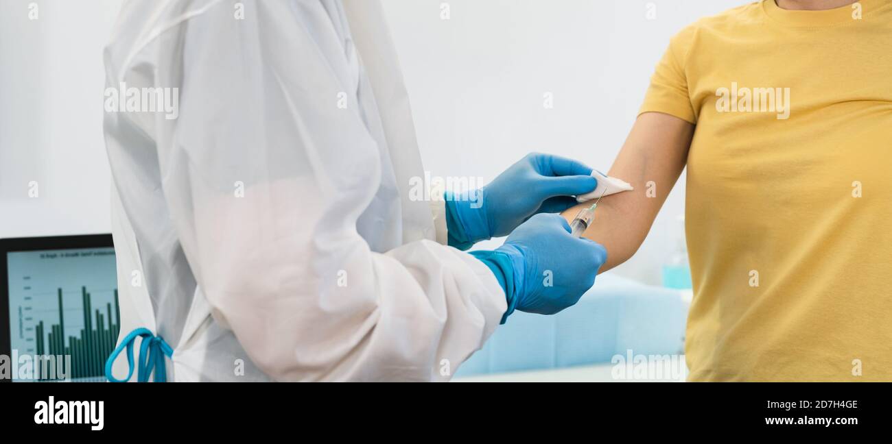 Doctor doing medical injection syringe vaccine to young patient in hospital for preventing and stop corona virus outbreak Stock Photo