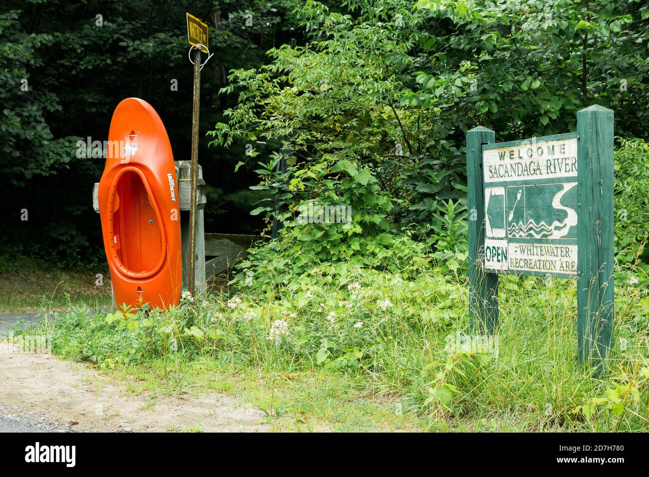Sacandaga River orange kayak boat & wooden sign, Saratoga county,  New York, USA.  Native American name Sa-chen-da'-ga, meaning 'overflowed lands'. Stock Photo