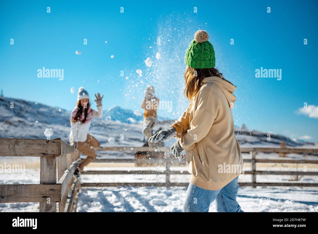 Happy adult girls are having fun and plays in snowballs at first snow in mountains Stock Photo