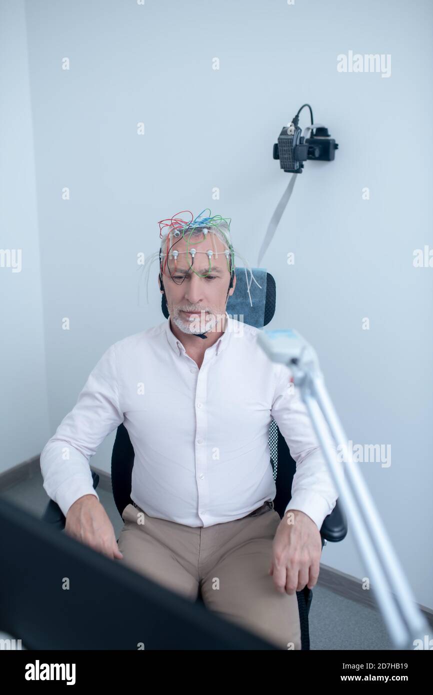 Serious gray-haired male patient undergoing electroencephalogram Stock Photo