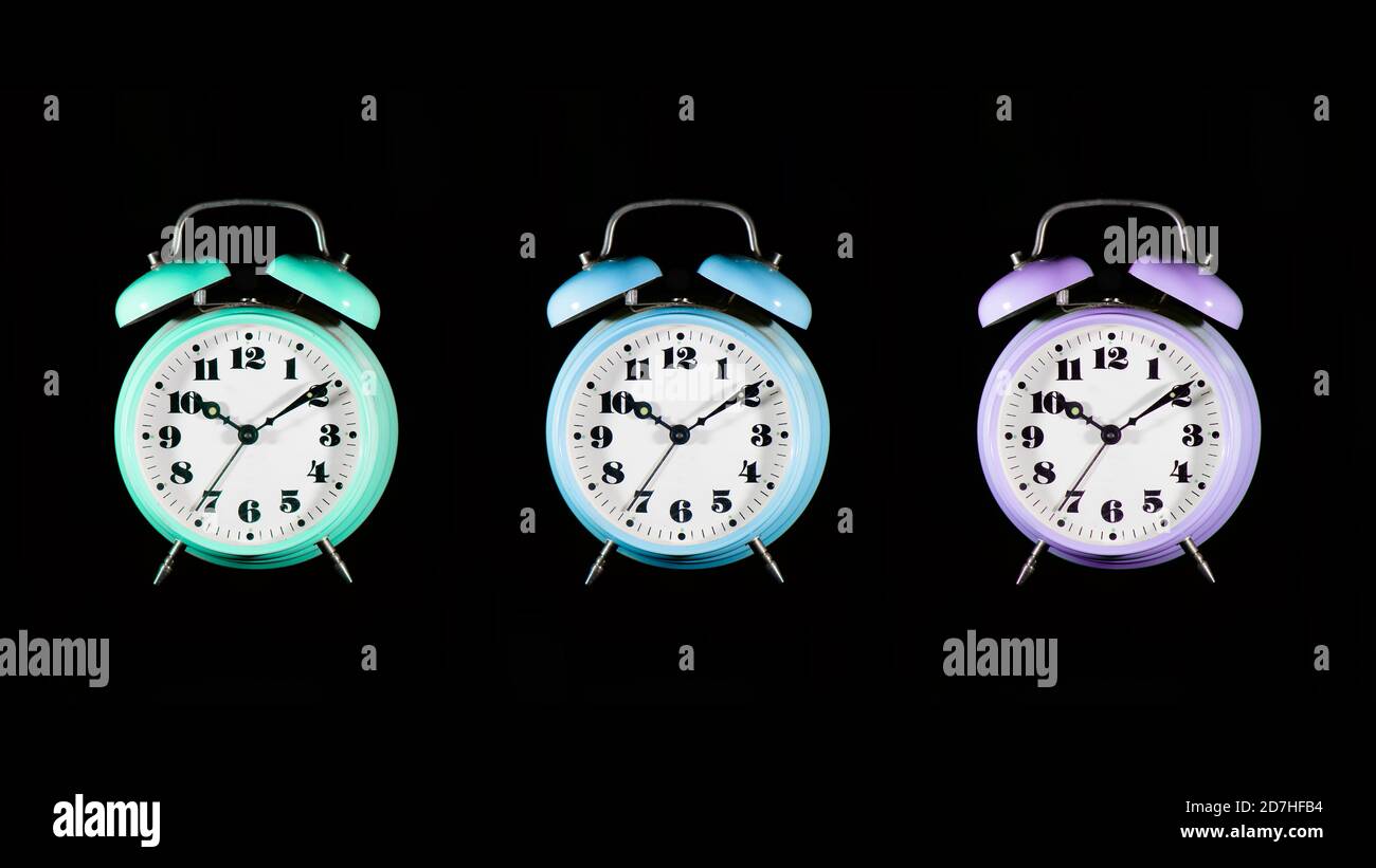Three colorful alarm clocks on a black background Stock Photo Alamy