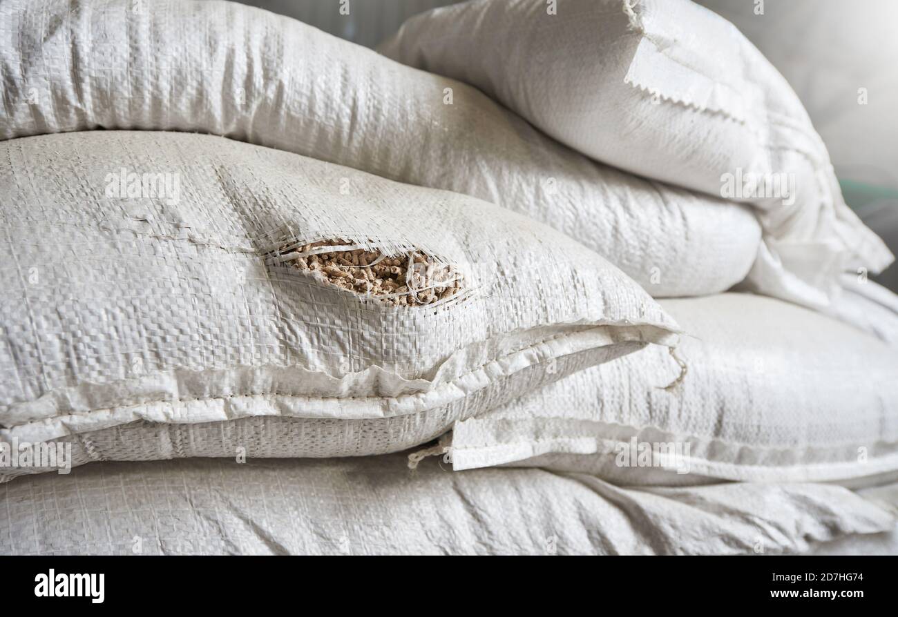 A hole in a white bag with animal feed in a warehouse Stock Photo