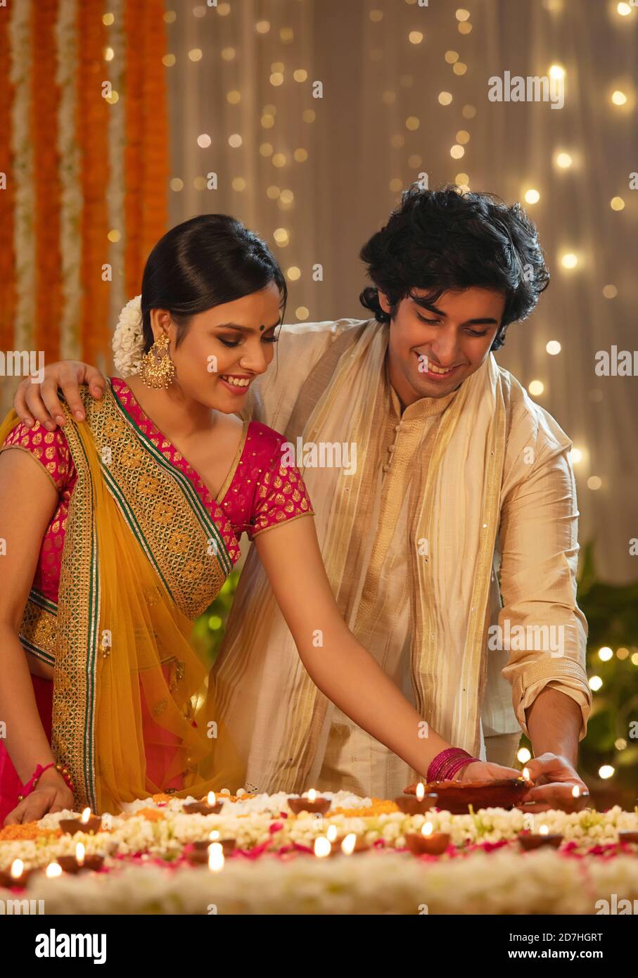 An Indian couple celebrating the festival of Diwali at home, lighting  candles and diyas Stock Photo - Alamy