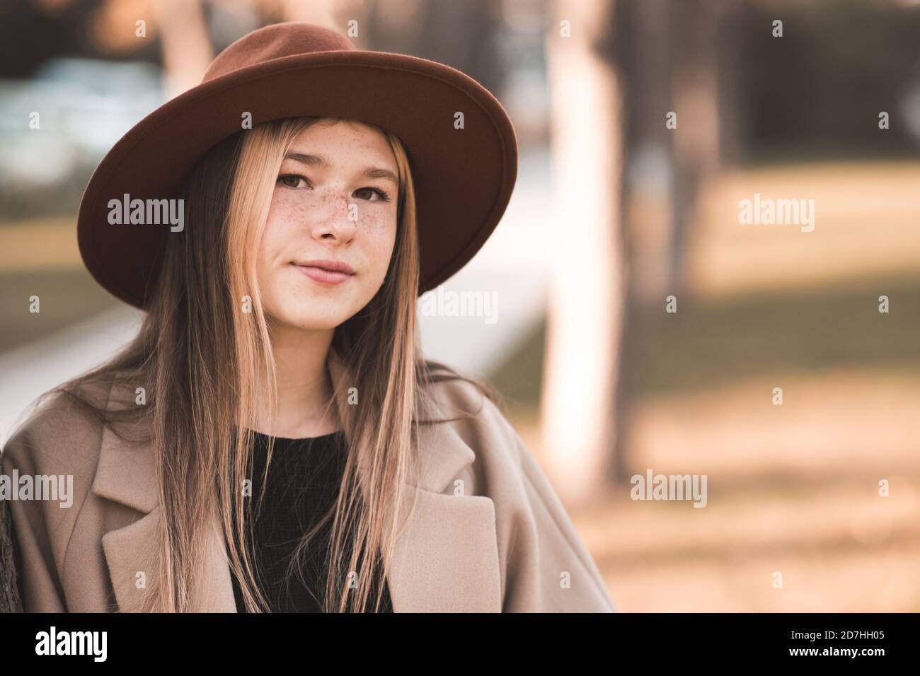 Beautiful blonde teen girl 13-14 year old wearing stylish clothes posing in  autumn park. Looking at camera Stock Photo - Alamy