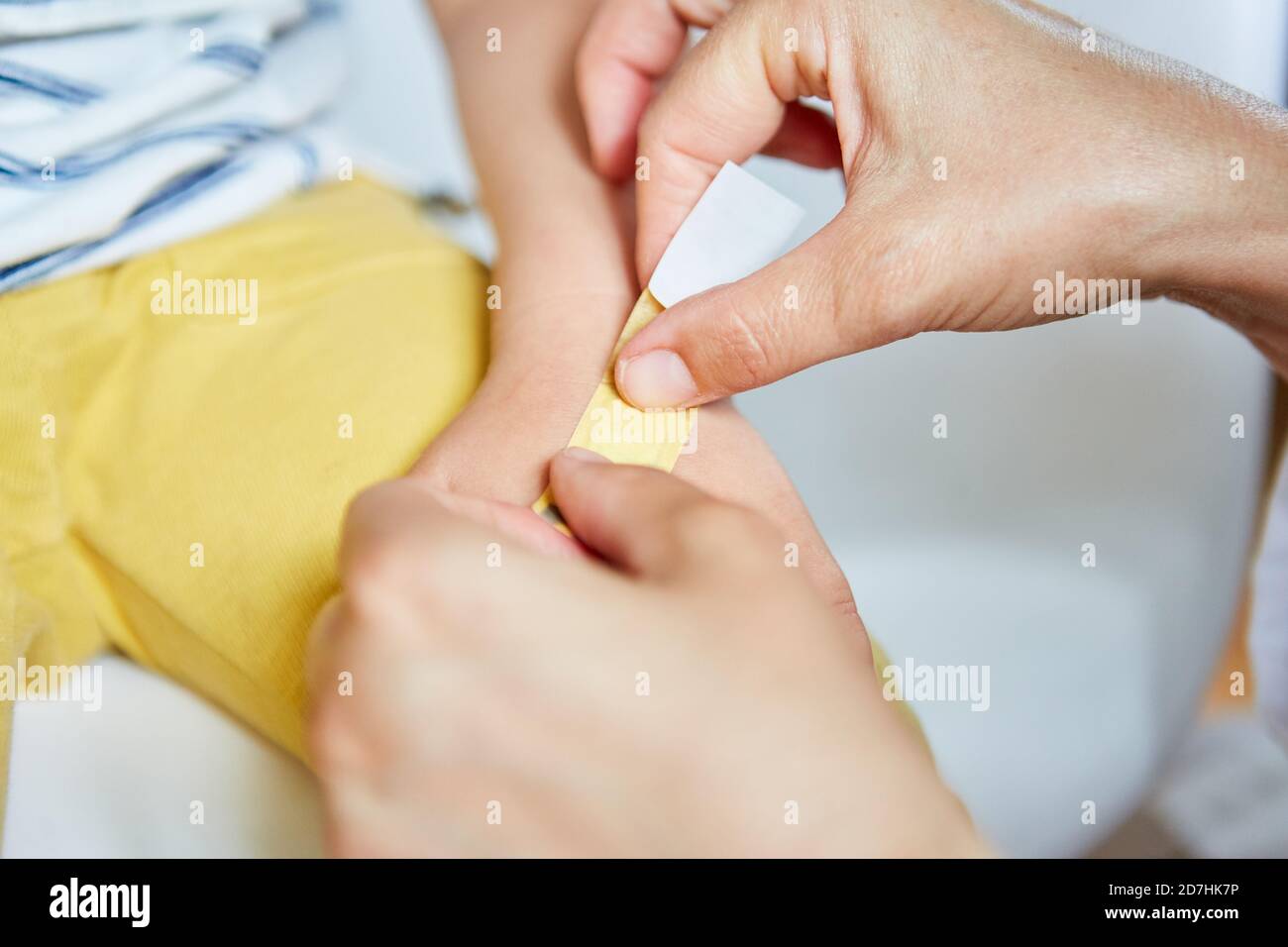 Pediatrician sticks a plaster on the injured hand of child after an accident Stock Photo