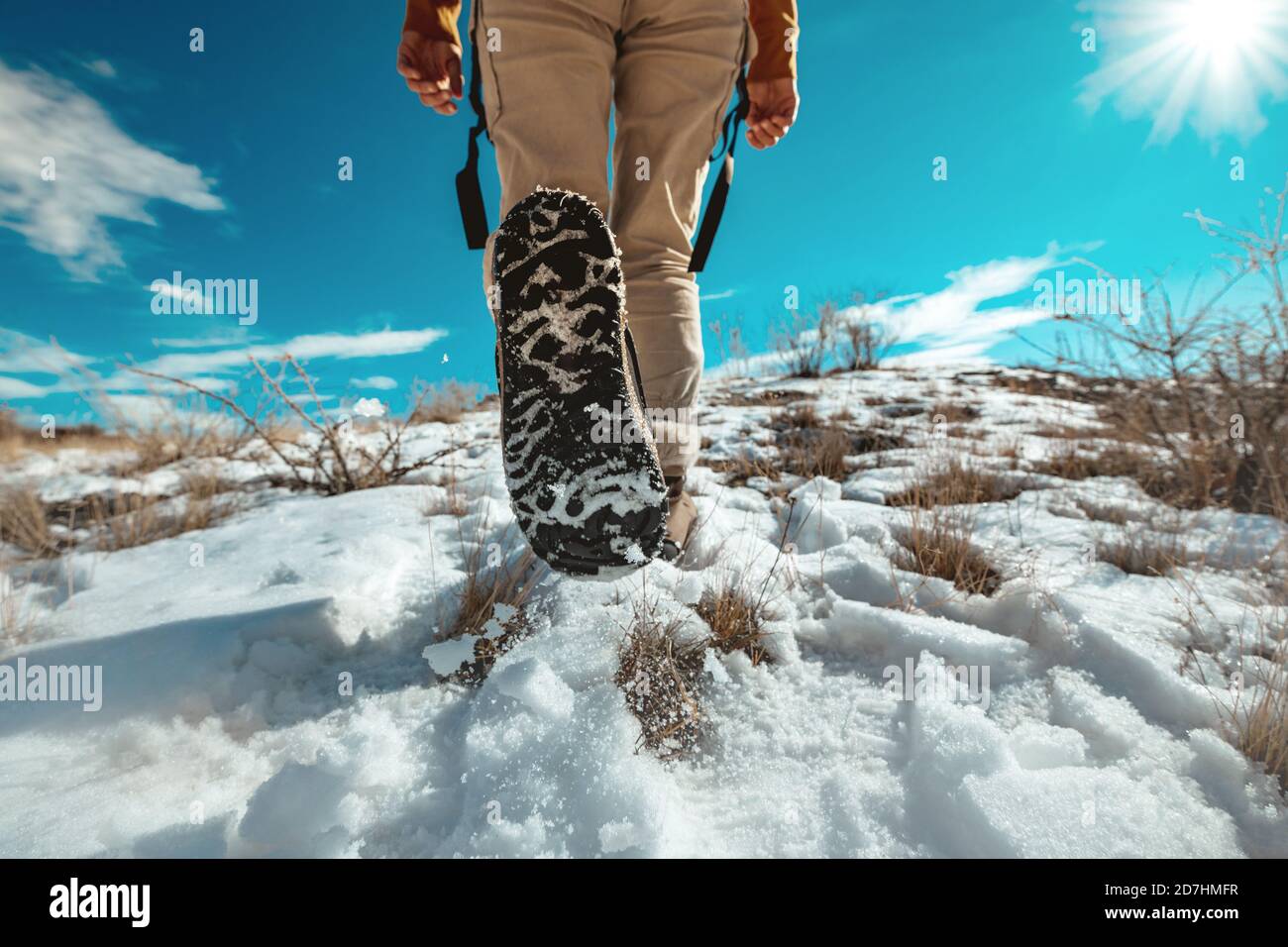 Lady hiker goes uphill by snowy surface. Closeup photo of woman legs Stock Photo