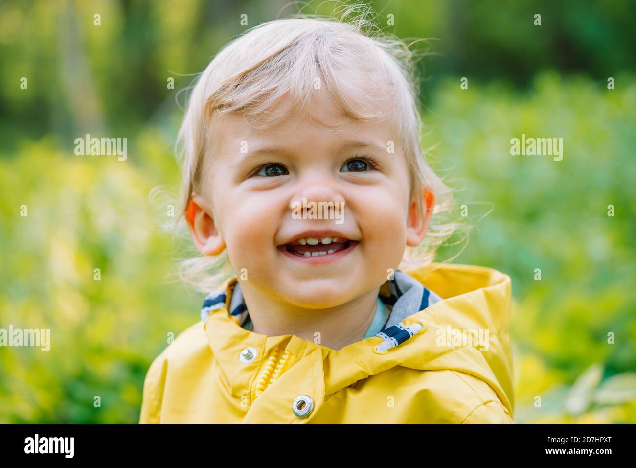 Portrait of cute baby boy in yellow raincoat. Child smiling. Love, care