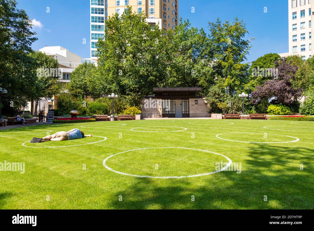 11th Aug 2020, London, UK - Circles drawn on grass at Westferry Circus, Canary Wharf to indicate social distancing spaces during coronavirus pandemic Stock Photo