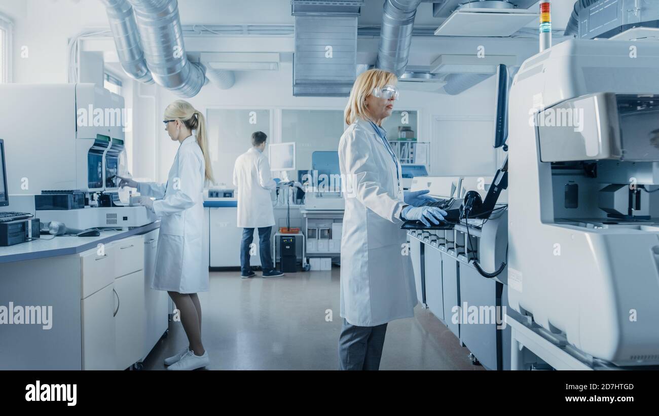 Team of Research Scientists Working On Computer, with Medical Equipment, Analyzing Blood and Genetic Material Samples with Special Machines in the Stock Photo