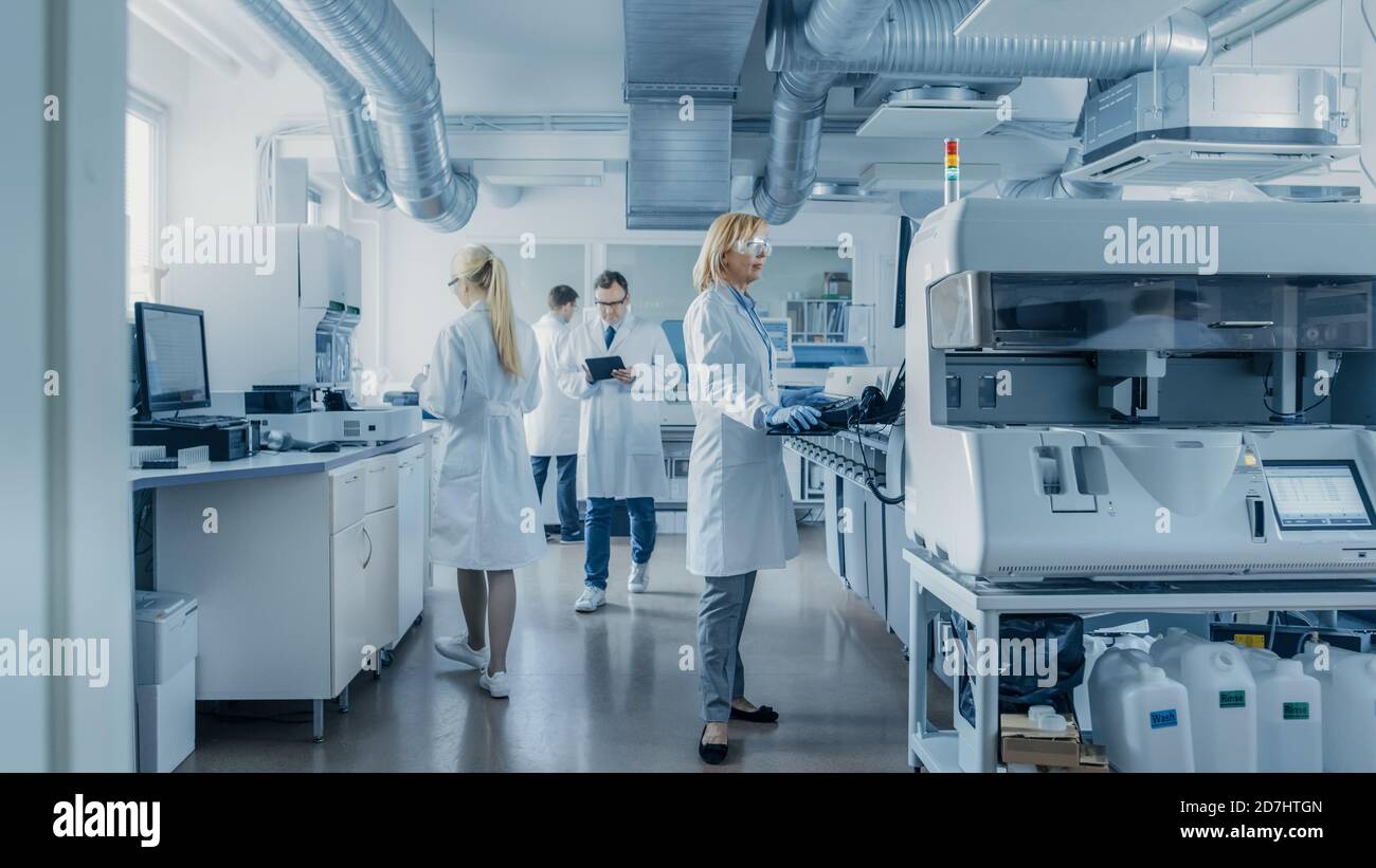 Team of Research Scientists Working On Computer, with Medical Equipment, Analyzing Blood and Genetic Material Samples with Special Machines in the Stock Photo