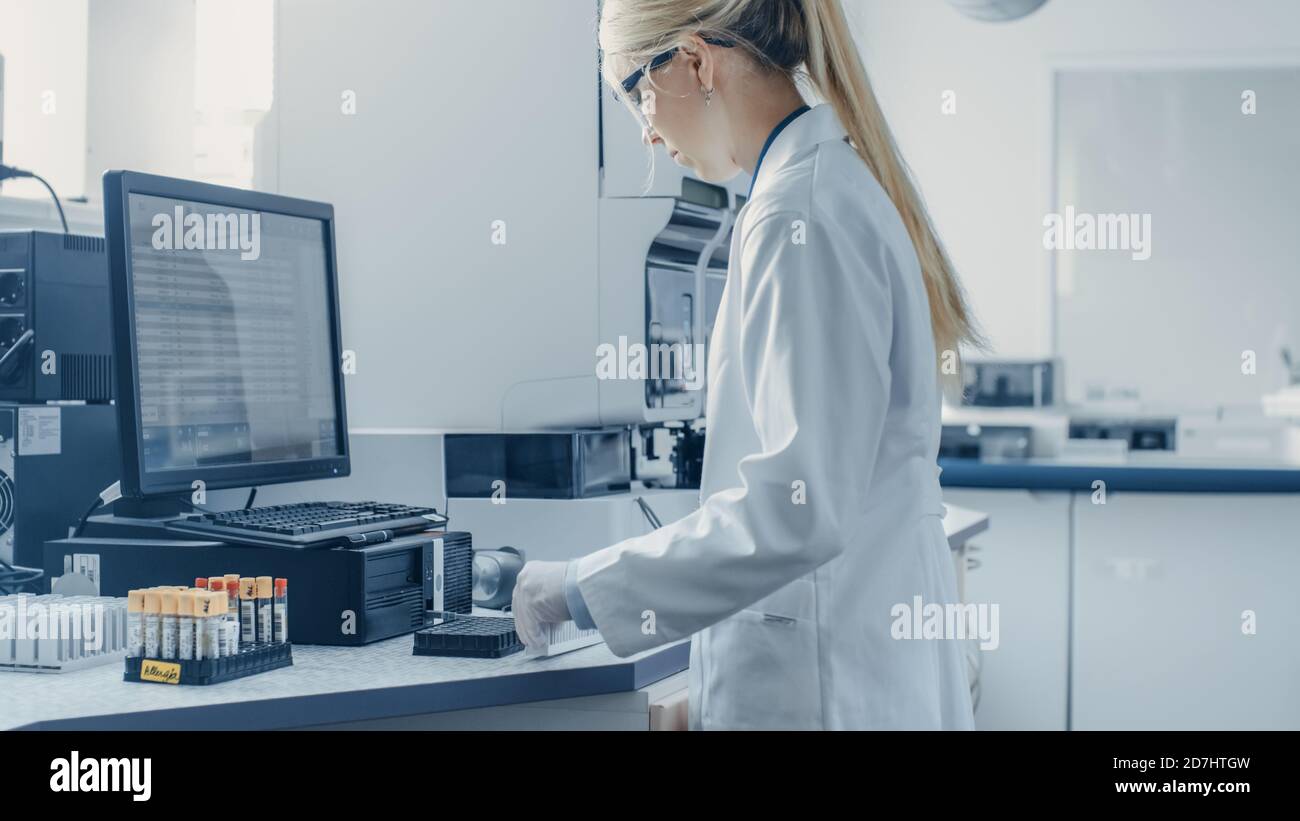 In Bio Technological Laboatory Female Research Scientist Analyzes Test Tube in Medical Machine, Works with Blood, Genetic Material Samples. Stock Photo