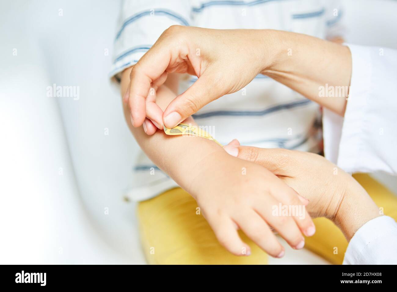 Pediatrician puts a plaster on the hand of a child with a sprain or bruise Stock Photo