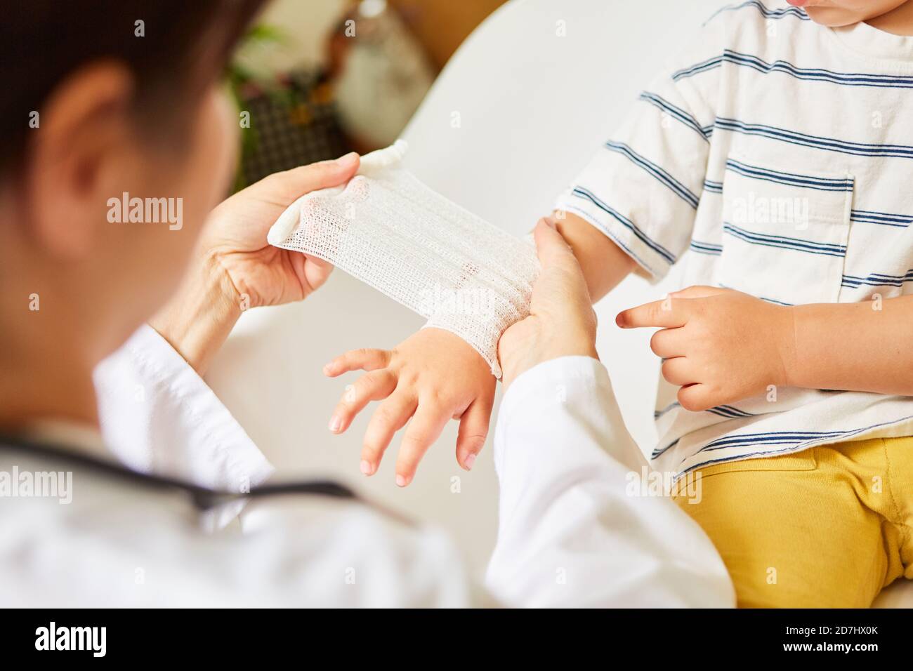 Pediatrician wraps bandage around child's wrist in the event of a sprain or accident Stock Photo