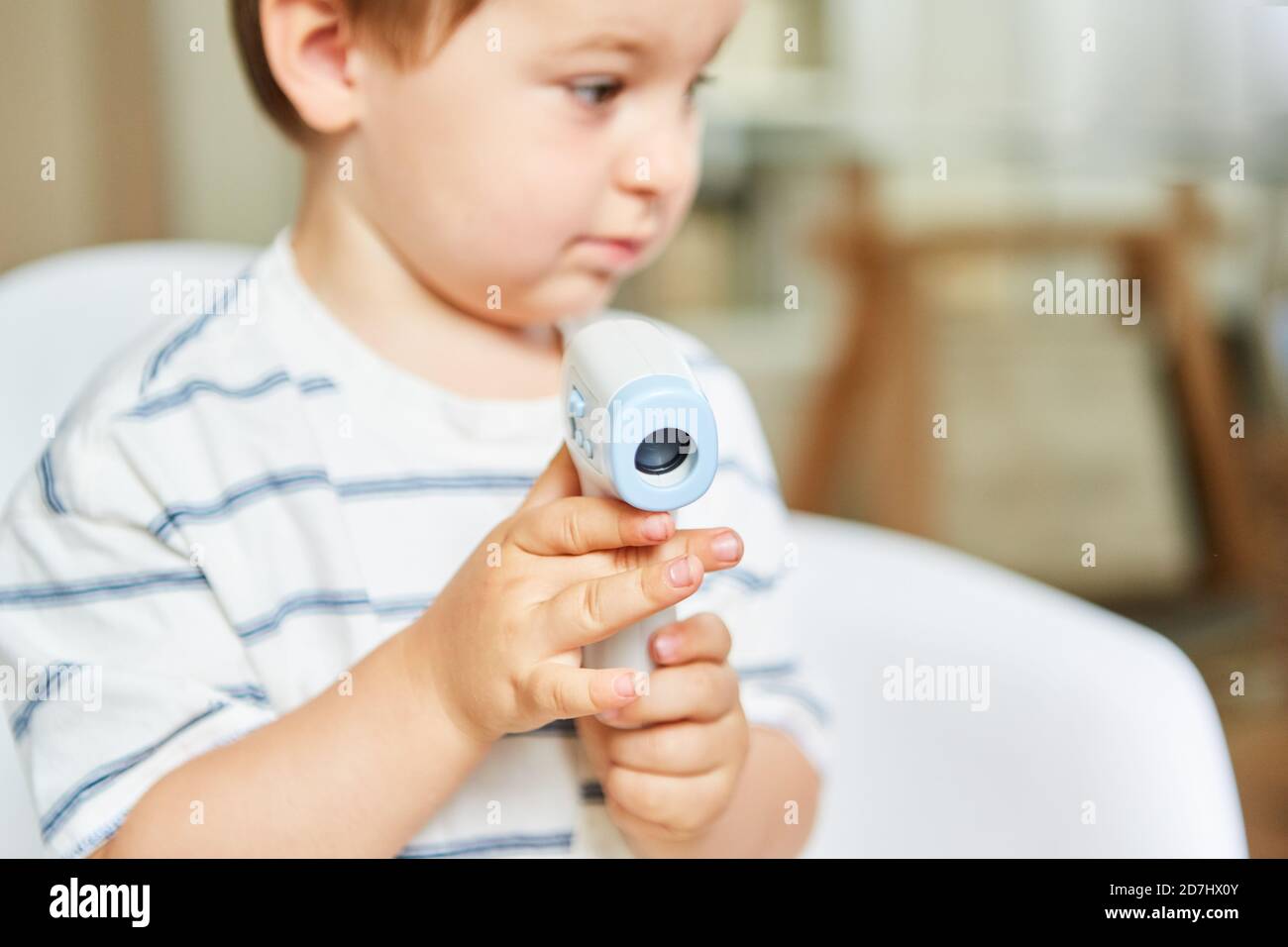 Child holds an infrared forehead thermometer for contactless measurement of a fever Stock Photo