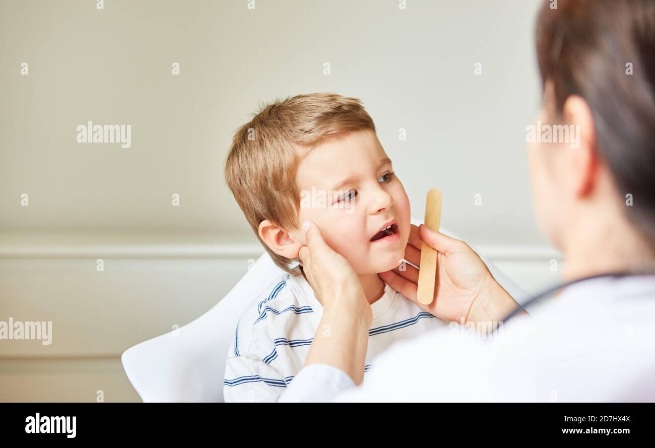 Pediatrician palpates tonsils and swollen lymph nodes in children with tonsillitis Stock Photo