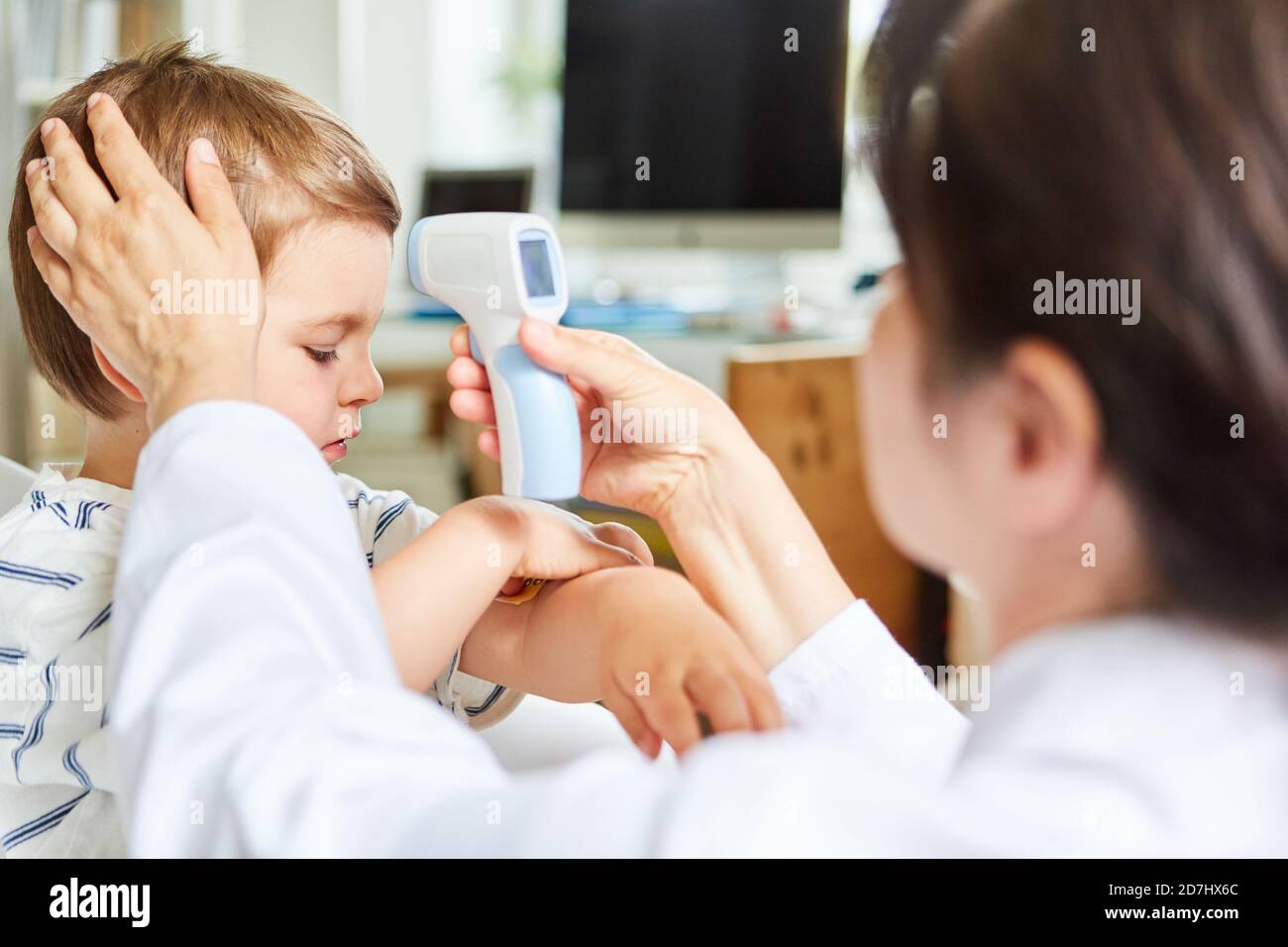 Pediatrician measuring a fever with a forehead thermometer on a child Stock Photo